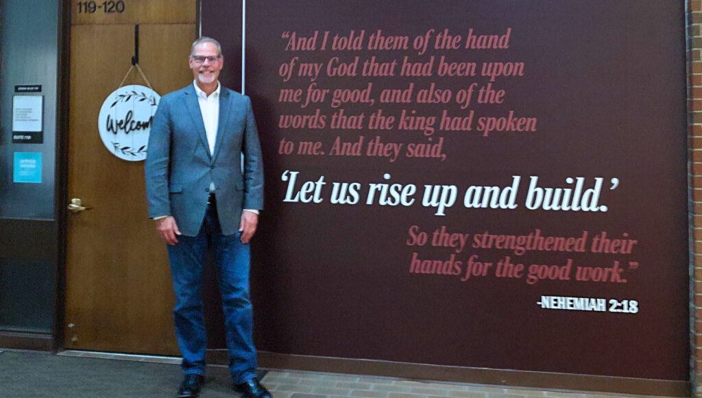 President Scott Moats in front of the new AU mission mural, Let Us Rise Up and Build