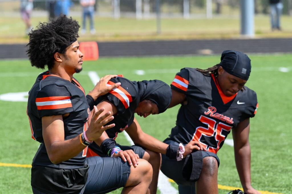 Three AU Footballers kneeling in prayer