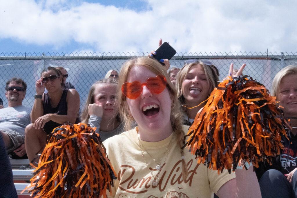 AU students cheer with pom-poms on the bleachers