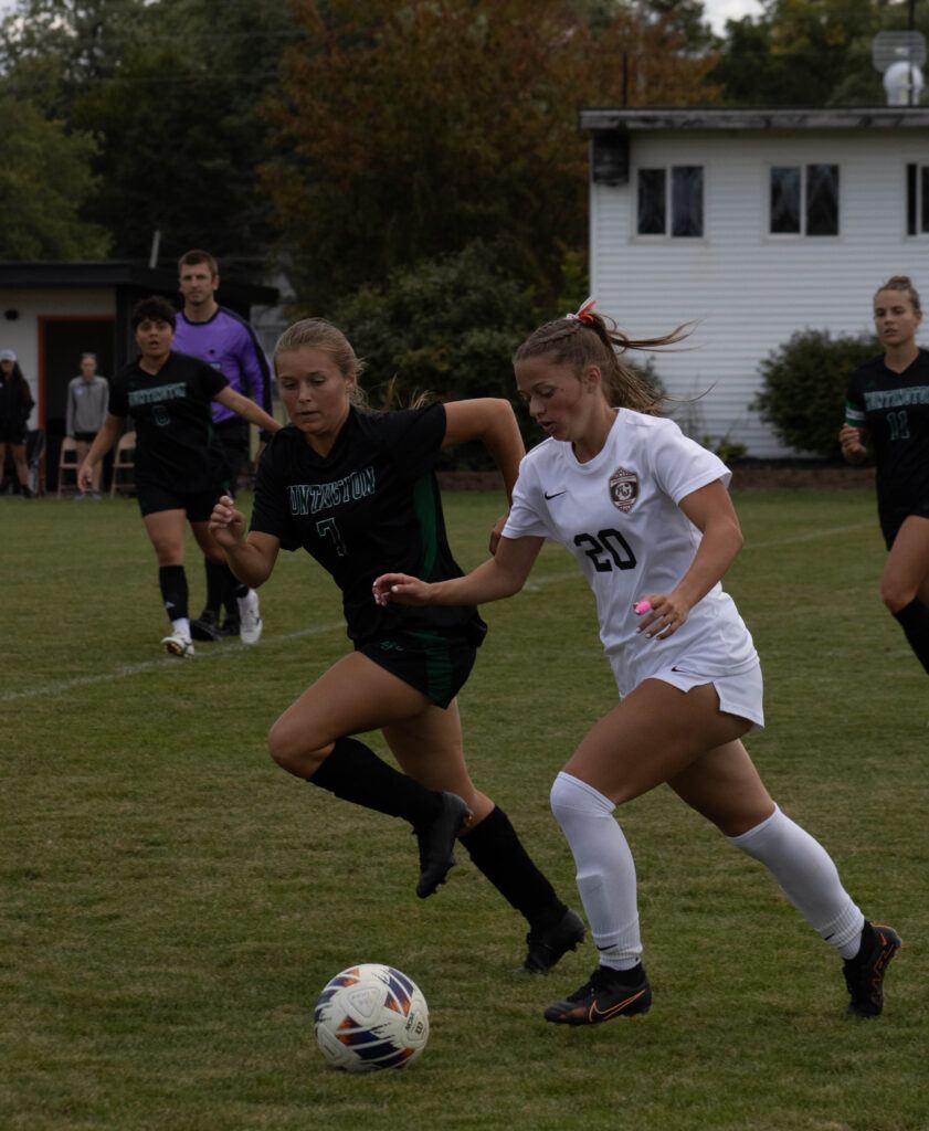 AU soccer player no. 20  dribbles the ball away from her opponent